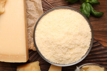 Delicious grated parmesan cheese in bowl on wooden table, flat lay