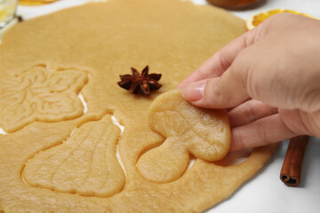 Woman holding uncooked mushroom shaped cookie at white table, closeup
