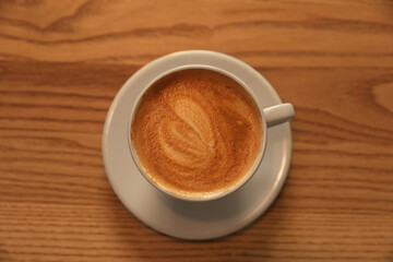 Cup of aromatic hot coffee on wooden table, top view