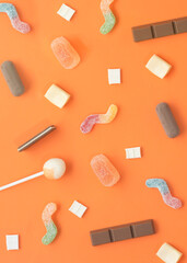 Candy pattern with gummy, chocolate, lollipop, gum, worm. Halloween trick or treat minimal concept on orange background.