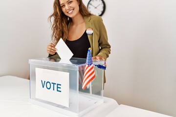 Young beautiful hispanic woman electoral table president putting vote in box at electoral college