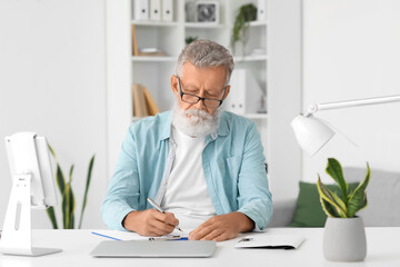 Senior bearded man working at table in office