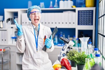 Fototapeta premium Beautiful woman working at scientist laboratory with food celebrating victory with happy smile and winner expression with raised hands