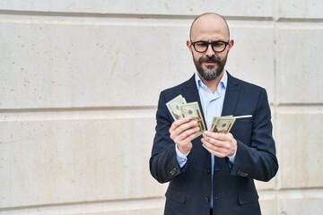 Young bald man business worker counting dollars at street