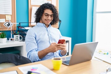 Young latin man business worker using laptop and smartphone at office