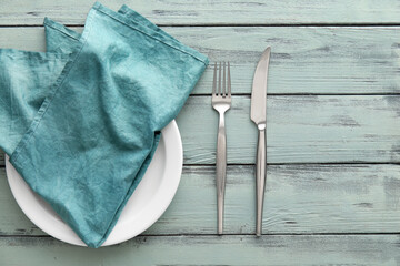 Table setting with napkin in plate and cutlery on color wooden background