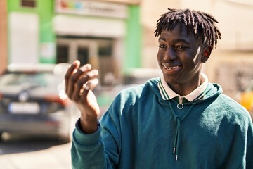 African american man smiling confident doing coming gesture with hand at street