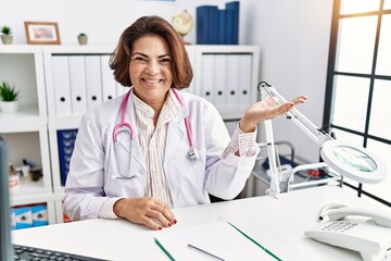 Middle age hispanic woman wearing doctor uniform and stethoscope at the clinic smiling cheerful...