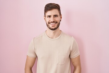 Hispanic man with beard standing over pink background with a happy and cool smile on face. lucky person.
