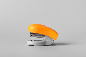 Orange office stapler on grey background
