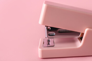 Office stapler on pink background, closeup