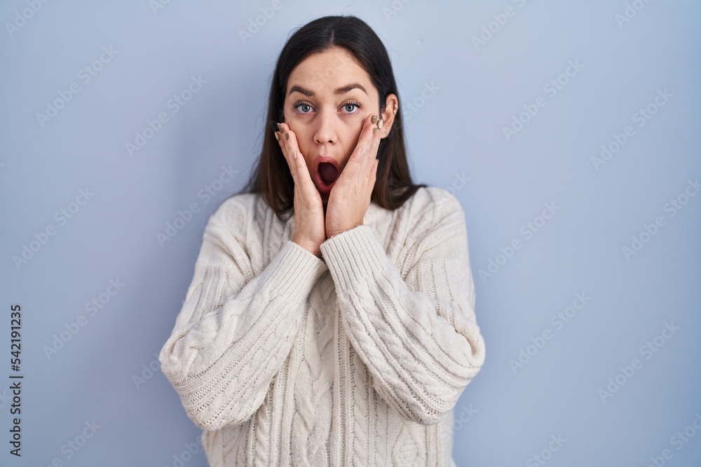 Poster young brunette woman standing over blue background afraid and shocked, surprise and amazed expressio