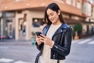 Young woman smiling confident using smartphone at street