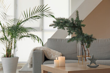 Vase with Christmas branches and candles on table in living room
