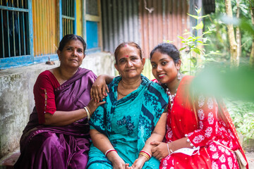 South asian family members sitting outside home wearing colourful traditional dress 