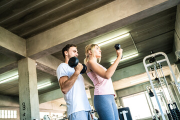 Fototapeta na wymiar Man and woman working out with dumbbell in fitnes sport gym