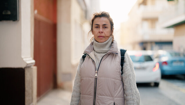 Middle age hispanic woman with relaxed expression standing at street