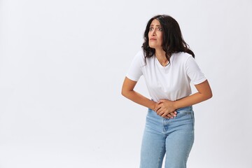 Woman pain during menstruation, abdominal pain appendicitis, age problems, early menopause, cystitis, a woman in a white t-shirt on a white background in jeans, copy space