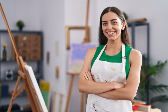 Young hispanic woman artist smiling confident standing with arms crossed gesture at art studio