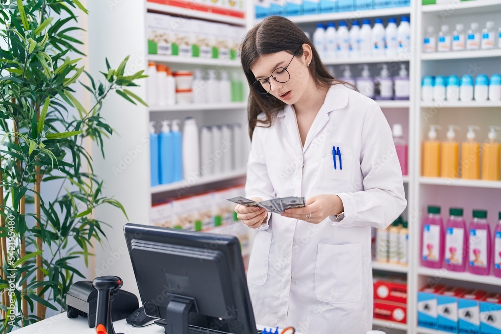 Sticker Young caucasian woman pharmacist smiling confident counting dollars at pharmacy