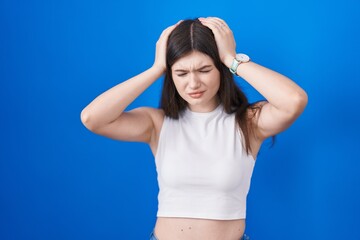 Fototapeta na wymiar Young caucasian woman standing over blue background suffering from headache desperate and stressed because pain and migraine. hands on head.