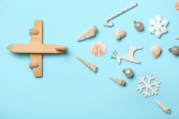 Wooden airplane with Christmas decor and seashells on blue background