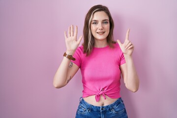 Obraz na płótnie Canvas Blonde caucasian woman standing over pink background showing and pointing up with fingers number seven while smiling confident and happy.