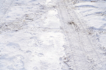 Texture of white winter country road, tire tracks and shoe prints in snow