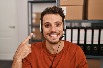 Young hispanic man wearing call center agent headset smiling happy pointing with hand and finger