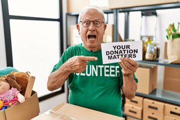 Senior volunteer man holding your donation matters smiling happy pointing with hand and finger