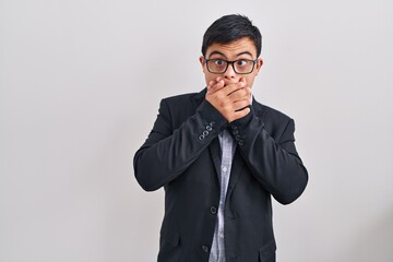Young hispanic man with down syndrome wearing business style shocked covering mouth with hands for mistake. secret concept.