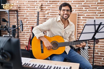 Young hispanic man musician playing classical guitar at music studio
