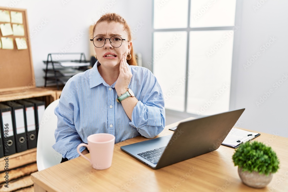 Poster young redhead woman working at the office using computer laptop touching mouth with hand with painfu