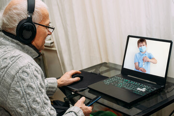 old man studies rules of hand disinfection. elderly man watches video where child shows how to use hand sterilizer