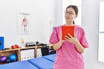 Young asian woman using touchpad device at physiotherapy clinic