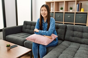 Young chinese girl smiling happy sitting on the sofa at home.
