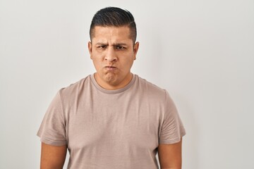Obraz premium Hispanic young man standing over white background skeptic and nervous, frowning upset because of problem. negative person.