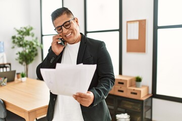 Young latin businessman talking on the smartphone working at the office.