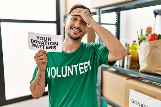 Young volunteer man holding your donation matters banner stressed and frustrated with hand on head, surprised and angry face