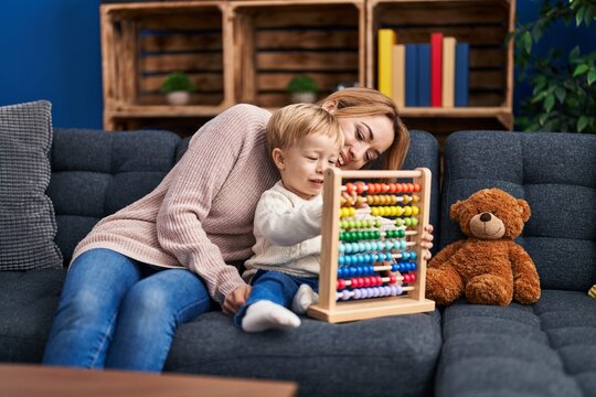 Mother and son playing with abacus sitting on sofa at home