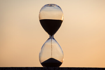 Hourglass on the background of a sunset. The value of time in life. An eternity.