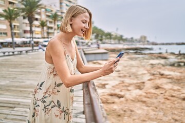 Fototapeta na wymiar Young beautiful woman using smartphone by the sea