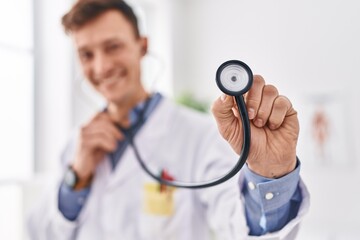 Young man doctor smiling confident holding stethoscope at clinic