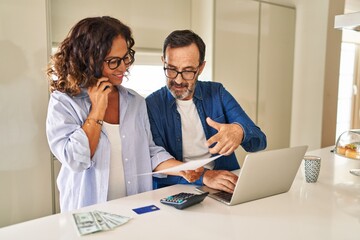 Obraz premium Middle age hispanic couple smiling confident controlling economy at kitchen