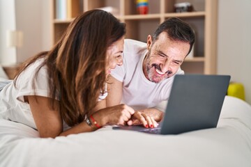 Fototapeta na wymiar Middle age man and woman couple using laptop lying on bed at bedroom