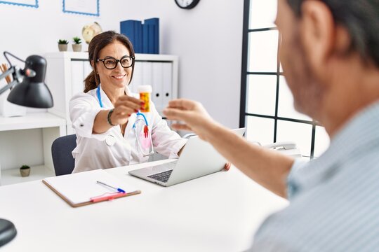 Middle age man and woman wearing doctor uniform prescribe pills at clinic