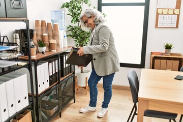 Middle age grey-haired businesswoman smiling happy working at the office.