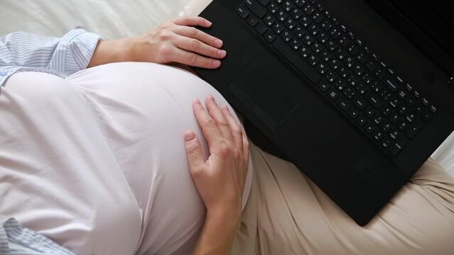 Beautiful young pregnant woman working on laptop at home