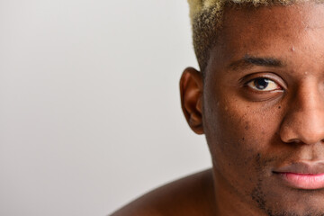 Close up shot of a half of the face of a young black man's skin. Face care concept. Macro studio shot on a beige background.