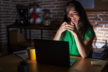 Young teenager girl working at the office at night pointing fingers to camera with happy and funny face. good energy and vibes.